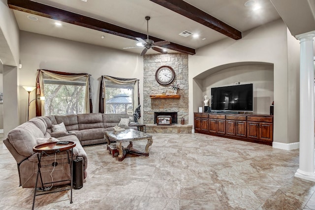 living room featuring decorative columns, ceiling fan, beamed ceiling, and a stone fireplace