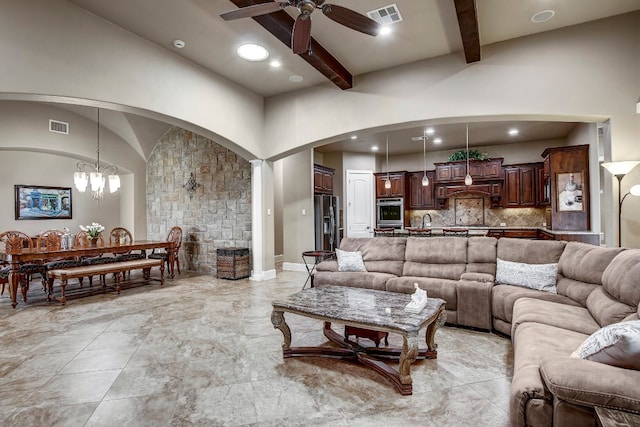 living room featuring ceiling fan with notable chandelier, beamed ceiling, high vaulted ceiling, and sink