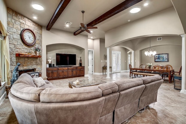 living room featuring beam ceiling, ceiling fan with notable chandelier, a fireplace, and decorative columns