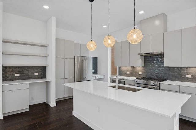 kitchen featuring sink, a kitchen island with sink, hanging light fixtures, premium appliances, and dark hardwood / wood-style flooring