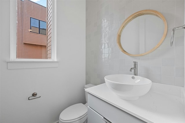 bathroom featuring vanity, toilet, and tile walls