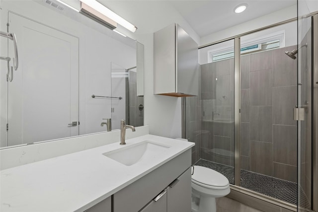 bathroom featuring vanity, a shower with door, and toilet