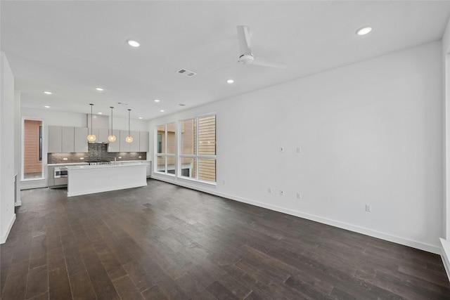 unfurnished living room featuring dark hardwood / wood-style flooring and ceiling fan