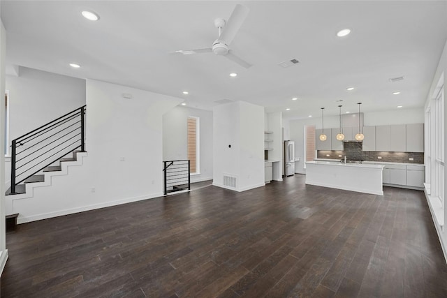 unfurnished living room featuring dark wood-type flooring, sink, and ceiling fan