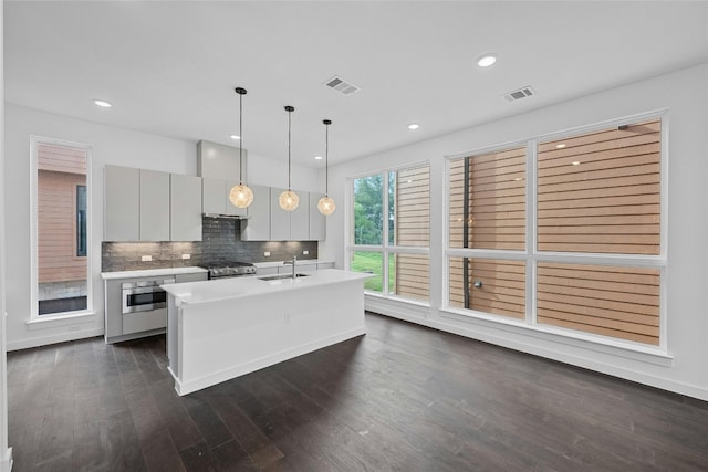 kitchen featuring pendant lighting, sink, stainless steel stove, oven, and wall chimney exhaust hood