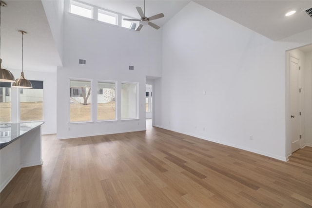 unfurnished living room with ceiling fan, wood-type flooring, and high vaulted ceiling