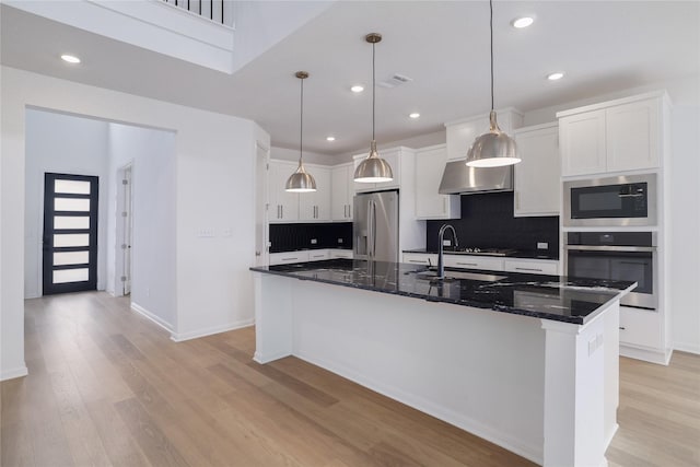 kitchen featuring appliances with stainless steel finishes, white cabinetry, sink, hanging light fixtures, and a kitchen island with sink