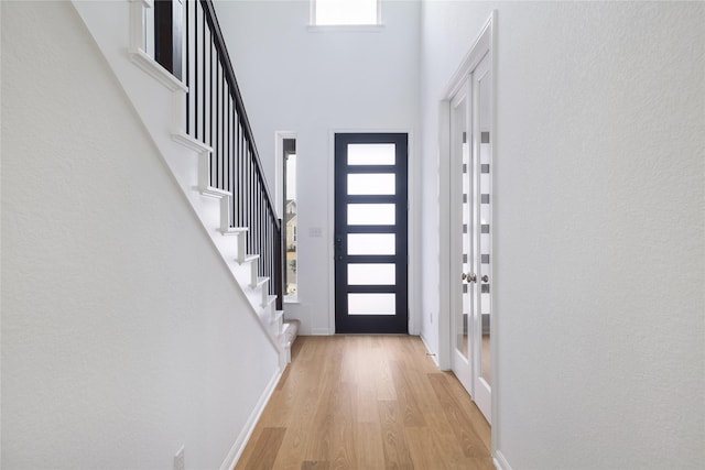 entryway featuring a high ceiling, plenty of natural light, and light wood-type flooring