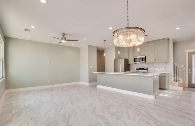 kitchen with ceiling fan with notable chandelier, gray cabinets, appliances with stainless steel finishes, and hanging light fixtures