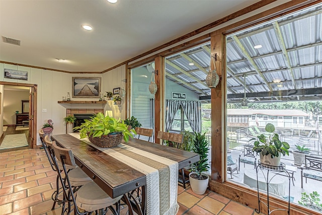 dining room with ornamental molding, a tiled fireplace, and vaulted ceiling