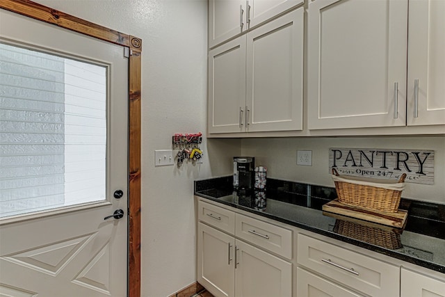 kitchen featuring dark stone counters, white cabinets, and plenty of natural light