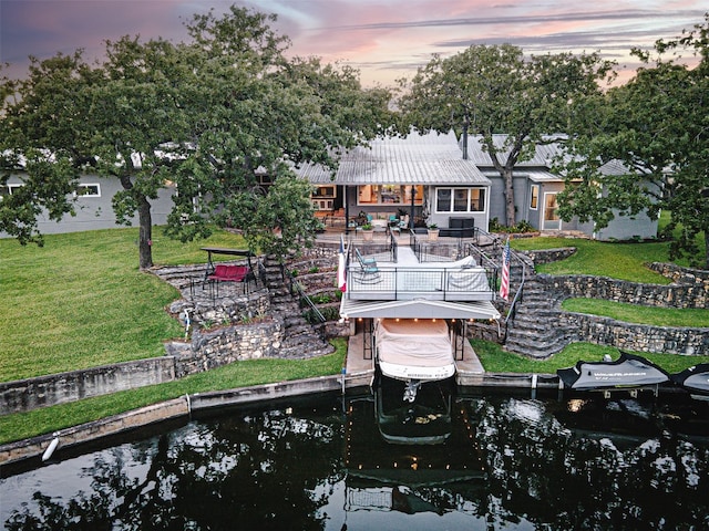 back house at dusk with a yard and a water view