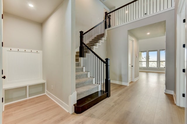 stairs with a towering ceiling and wood-type flooring