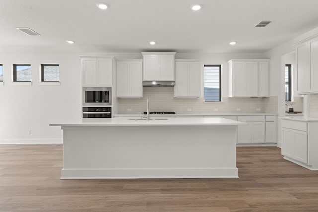 kitchen with white cabinetry, a kitchen island with sink, light hardwood / wood-style flooring, and black appliances