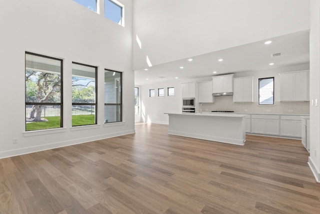 unfurnished living room featuring sink and light hardwood / wood-style flooring