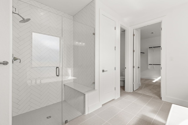 bathroom featuring tile patterned floors, toilet, and a shower with shower door