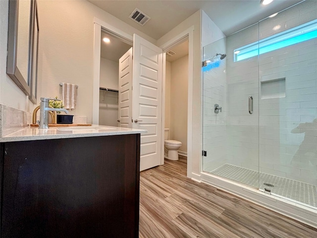 bathroom featuring hardwood / wood-style flooring, vanity, toilet, and walk in shower