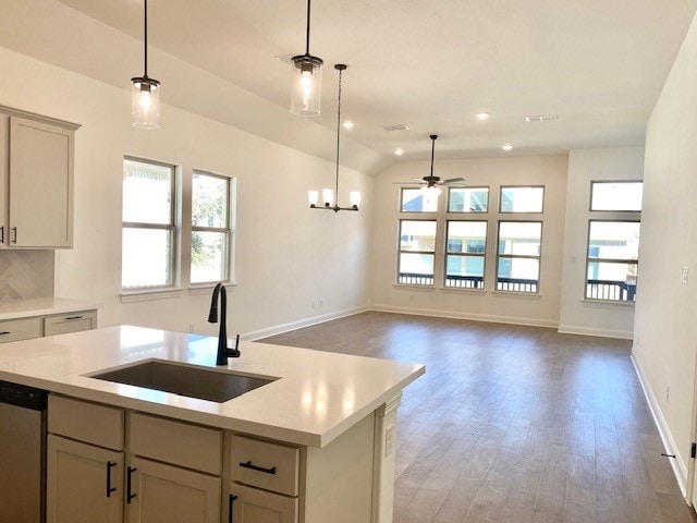 kitchen featuring a kitchen island with sink, ceiling fan with notable chandelier, sink, stainless steel dishwasher, and gray cabinets