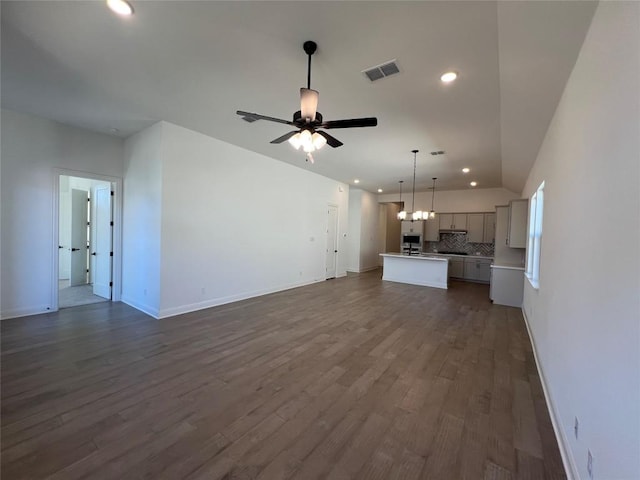 unfurnished living room with dark wood-type flooring and ceiling fan with notable chandelier