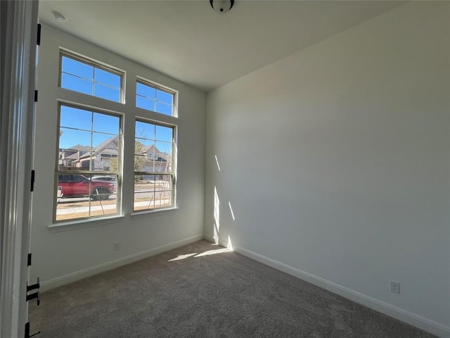 unfurnished room featuring dark carpet