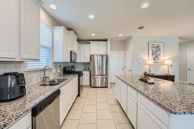 kitchen with white cabinets, appliances with stainless steel finishes, sink, and a kitchen island