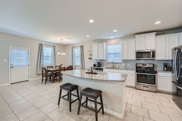 kitchen with a chandelier, a center island, sink, hanging light fixtures, and appliances with stainless steel finishes