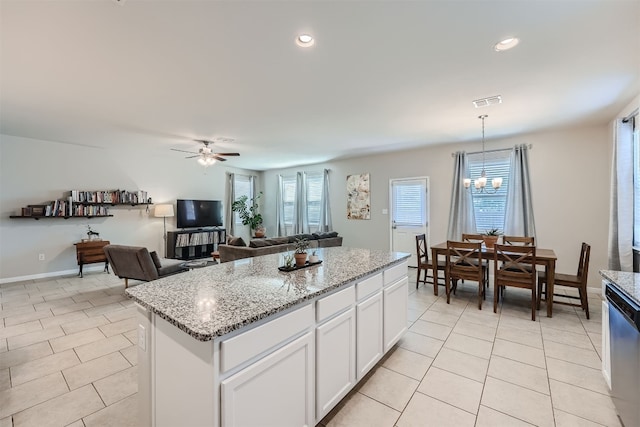 kitchen featuring stainless steel dishwasher, decorative light fixtures, white cabinetry, a center island, and ceiling fan with notable chandelier