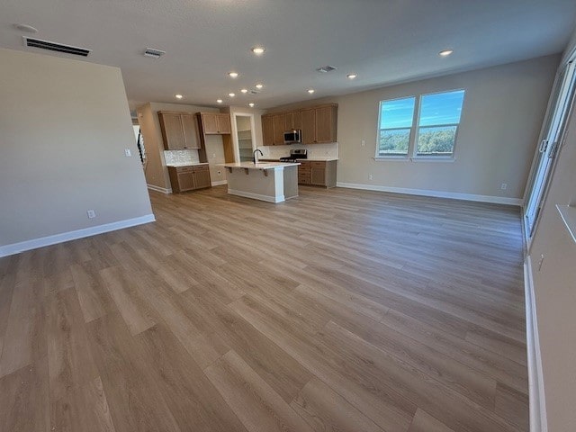 unfurnished living room featuring light hardwood / wood-style flooring and sink