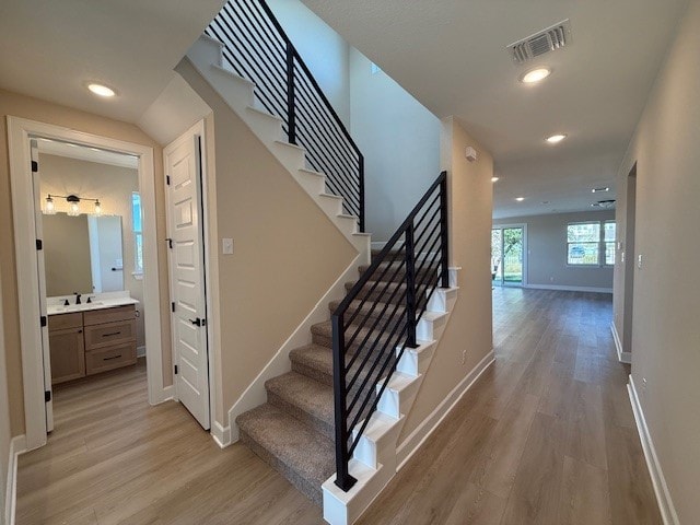 stairs featuring hardwood / wood-style floors and sink