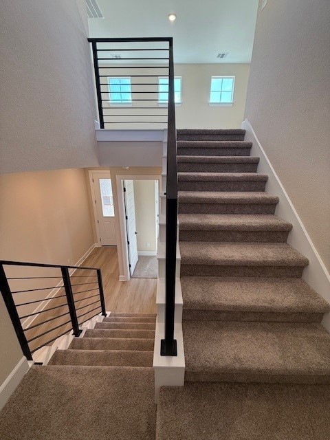 552 Raleigh Dr, Georgetown, TX 78633 - stairway featuring baseboards, a towering ceiling, wood finished floors, and visible vents