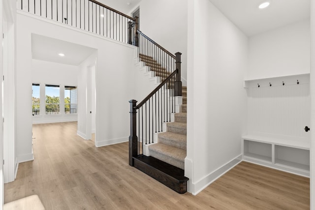 mudroom with a towering ceiling and light hardwood / wood-style floors