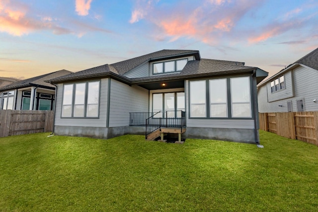 back house at dusk featuring a yard