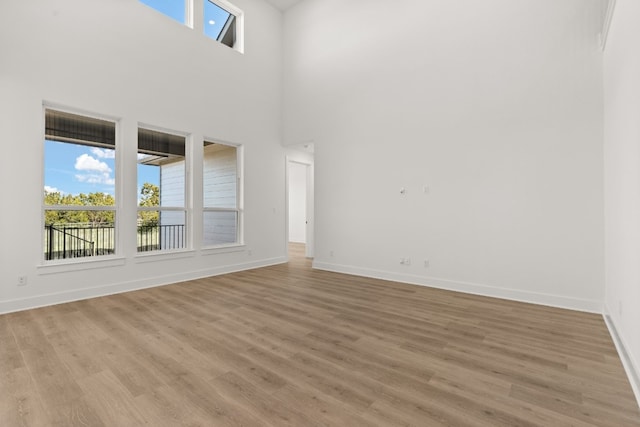 unfurnished living room with a high ceiling and light hardwood / wood-style floors