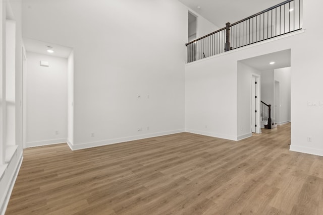 unfurnished living room with a high ceiling and light hardwood / wood-style floors