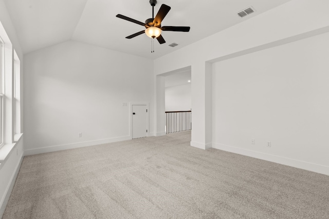 empty room with vaulted ceiling, light colored carpet, and ceiling fan