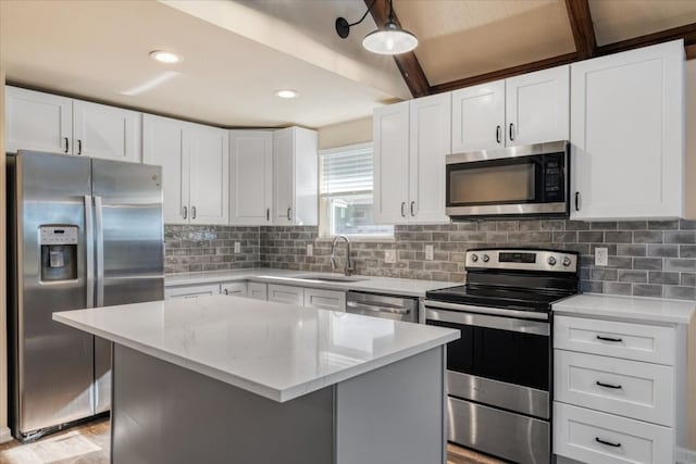 kitchen featuring white cabinets, stainless steel appliances, sink, and a center island