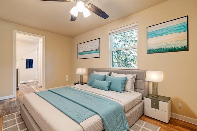 bedroom with light wood-style flooring, connected bathroom, baseboards, and ceiling fan