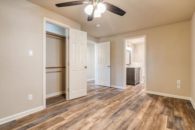 unfurnished bedroom with connected bathroom, dark wood-type flooring, ceiling fan, and a closet