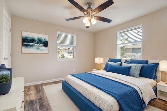 bedroom with baseboards, multiple windows, and wood finished floors