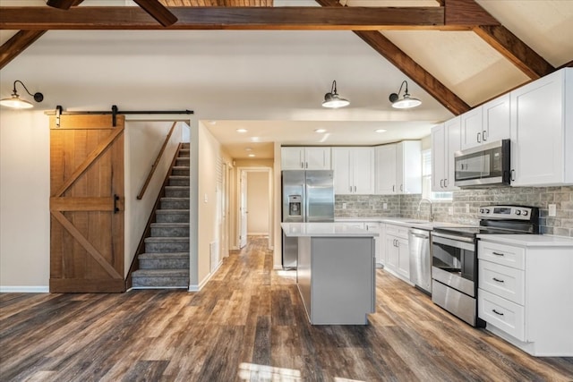 kitchen featuring white cabinets, a kitchen island, appliances with stainless steel finishes, dark hardwood / wood-style floors, and a barn door