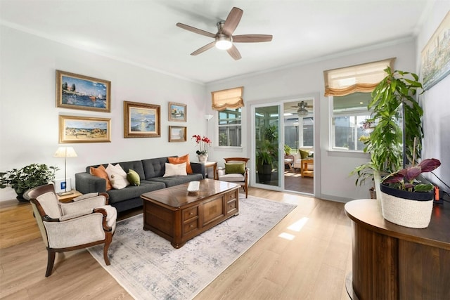 living room featuring light wood-style floors, ornamental molding, and a ceiling fan