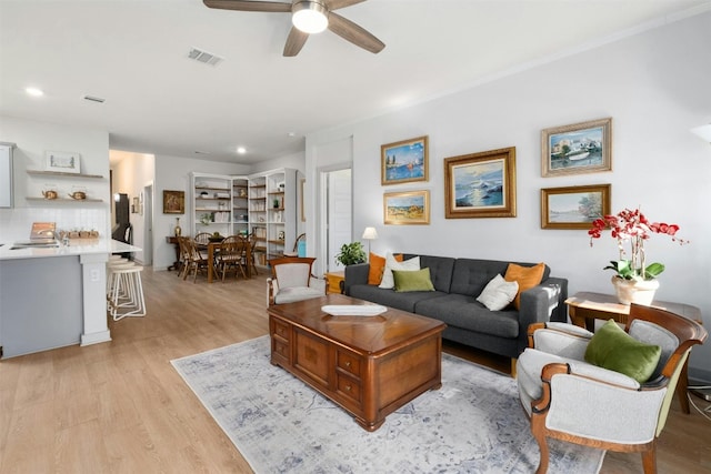 living room featuring light wood-type flooring, visible vents, a ceiling fan, and recessed lighting