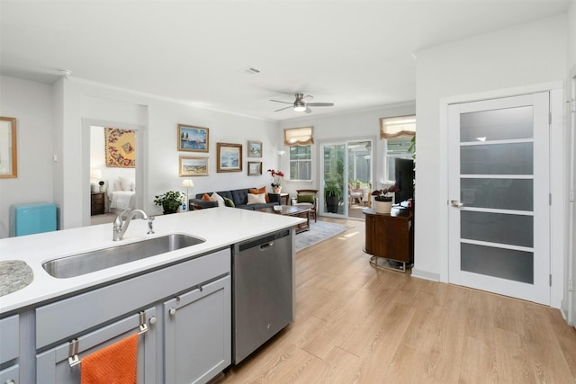 kitchen with a sink, open floor plan, light countertops, stainless steel dishwasher, and light wood finished floors