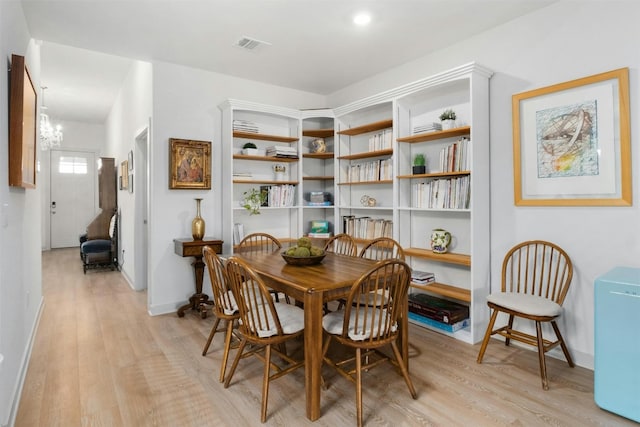 dining room with baseboards, a notable chandelier, visible vents, and light wood finished floors