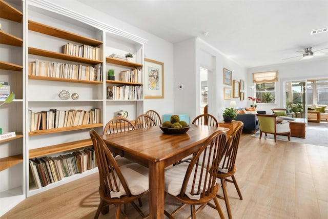 dining room with light wood-type flooring, visible vents, and a ceiling fan