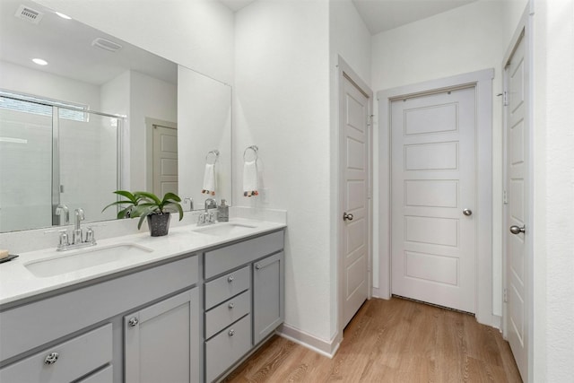 bathroom with double vanity, wood finished floors, a sink, and visible vents