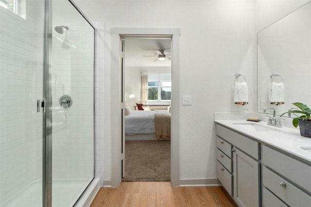 ensuite bathroom with double vanity, a sink, a shower stall, ensuite bath, and wood finished floors