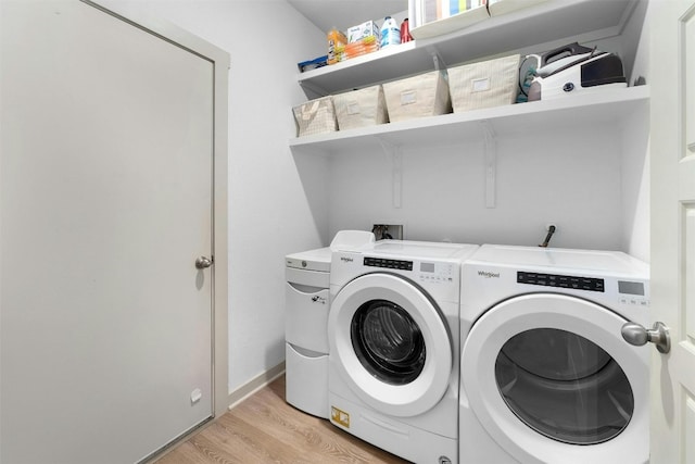 laundry area featuring laundry area, light wood-type flooring, washing machine and dryer, and baseboards