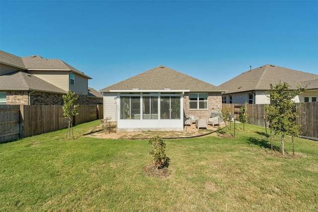 back of house with a lawn, a shingled roof, a fenced backyard, and a sunroom