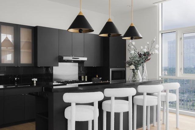 kitchen featuring a breakfast bar, backsplash, light hardwood / wood-style floors, and sink